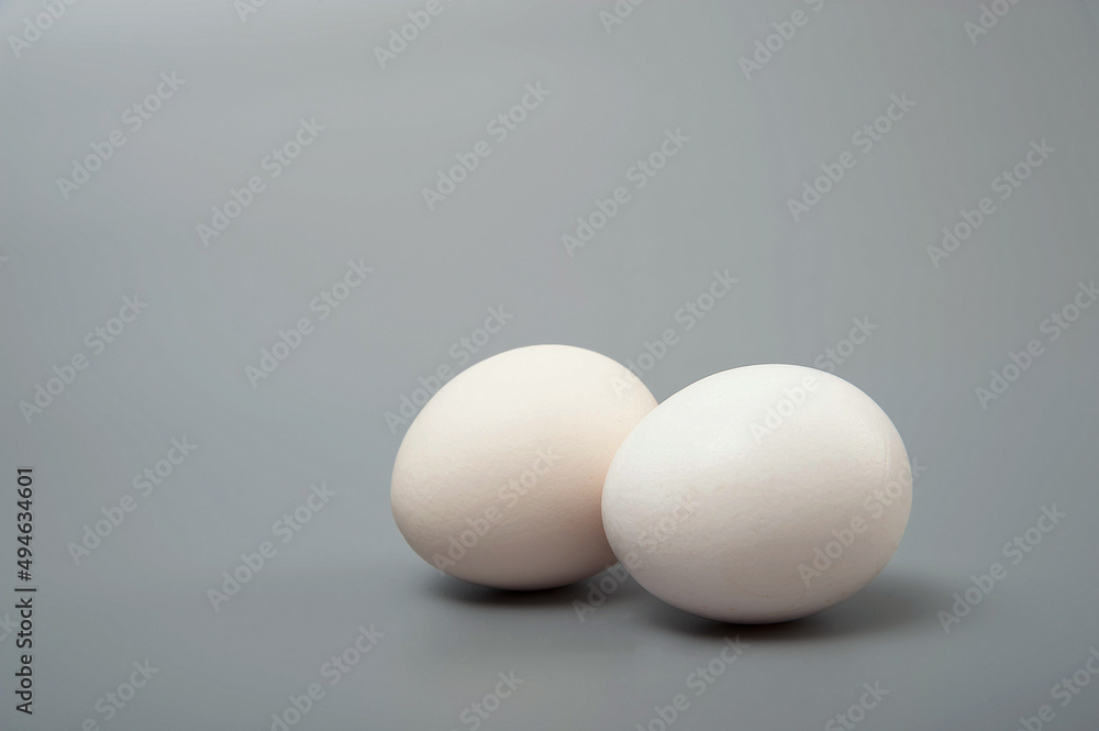 Two white eggs on a gray background. Minimalism. Healthy food concept. Two white eggs on a gray background. Minimalism. Healthy food concept.