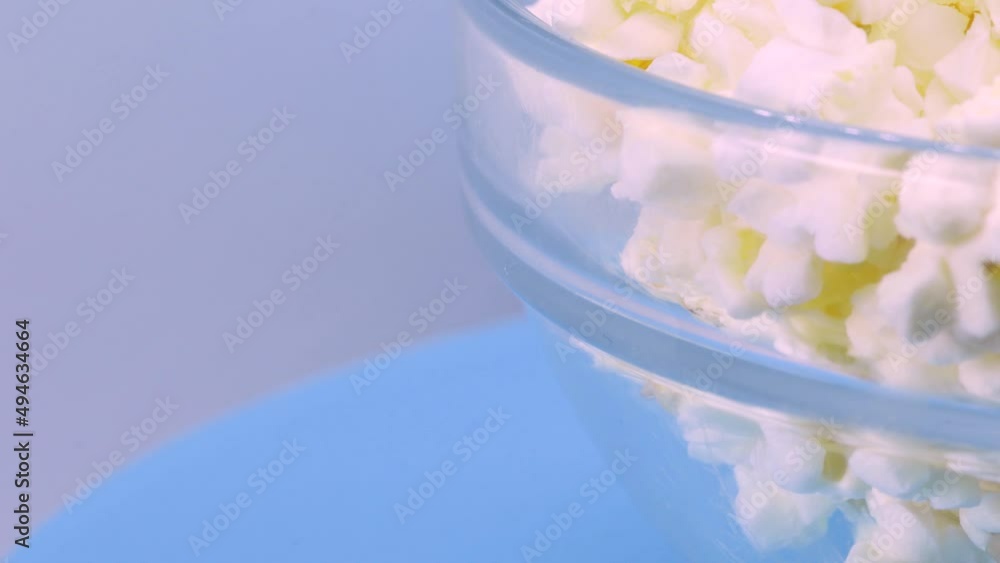 Bowl of popcorn rotating over a blue surface, macro shot in 4k. Bowl of popcorn rotating over a blue surface, macro shot in 4k.