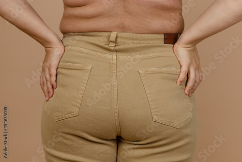 Closeup of lady back of large waist with love handles, sides having jeans on. Body positive. Accepting who you are. Tight clothes. Need for wardrobe change.