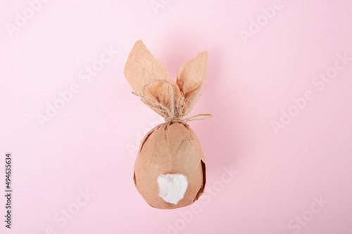 Easter minimal concept. Easter bunny paper gift egg wrap diy idea. Pink background. Decoration. 