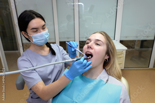 female dentist drills a tooth to a female patient in a dental studio. Dental treatment.