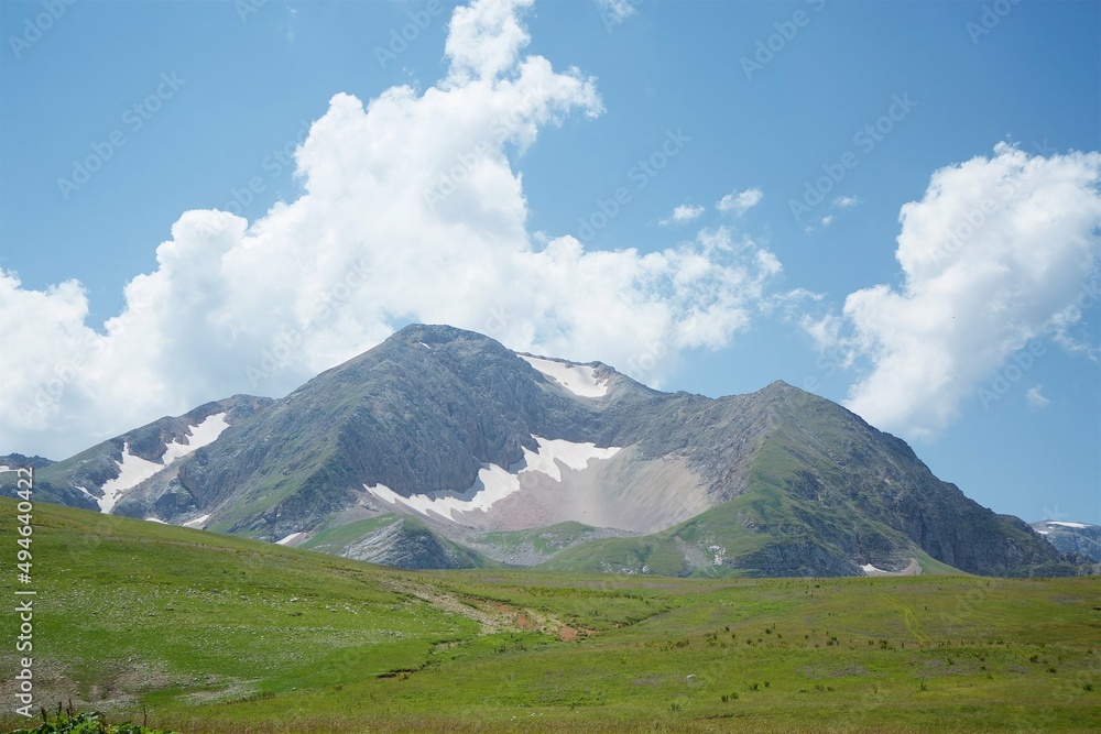 Summer mountain landscape. High mountains and above the mountains a bright blue sky Summer mountain landscape. High mountains and above the mountains a bright blue sky