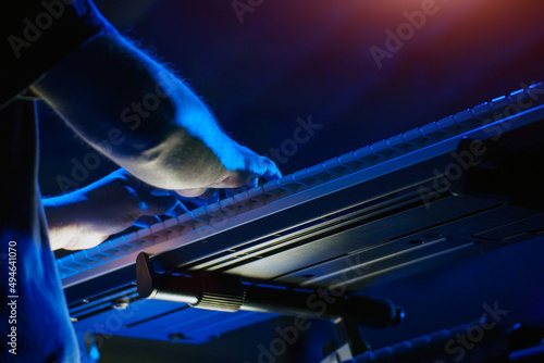 A pianist or keyboardist plays on stage a synthesizer in the spotlight. Dark key. Soft selective focus photo