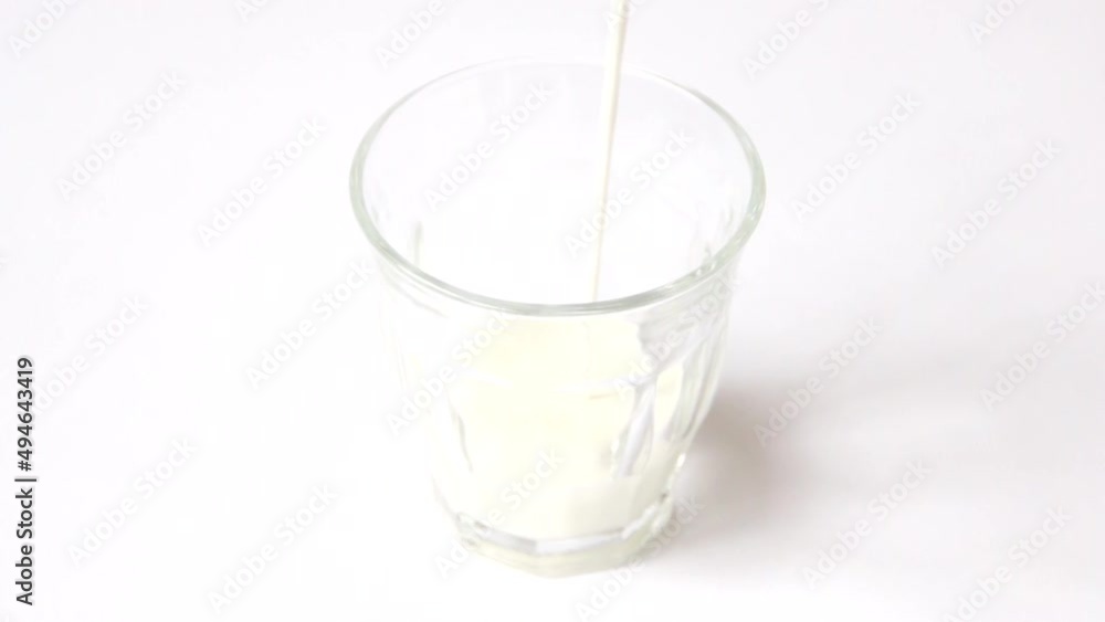 ガラスのコップにそそがれている牛乳の映像。白いテーブルの上にグラスがひとつおかれていてシンプルな印象がある映像。 ガラスのコップにそそがれている牛乳の映像。白いテーブルの上にグラスがひとつおかれていてシンプルな印象がある映像。