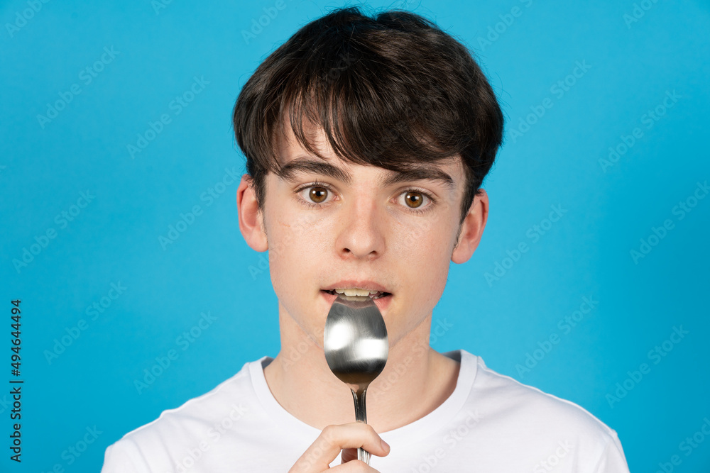 Portrait of cute teenager boy biting spoon Portrait of cute teenager boy biting spoon