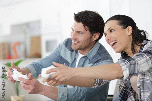 happy young couple having fun playing videogames at home