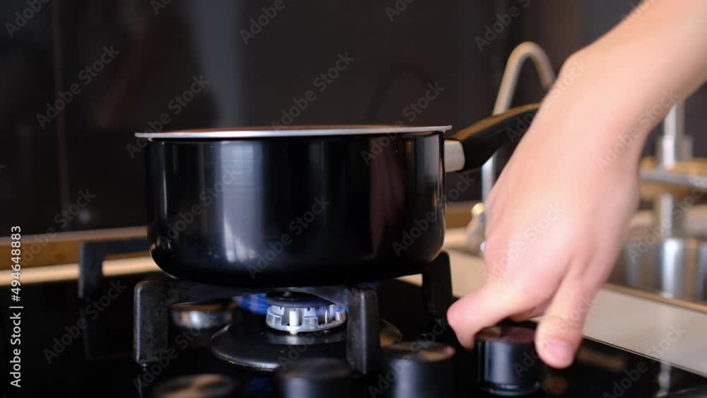 Closeup shot female hands puts pot on gas stove, turns on gas to cook lunch or dinner for whole family. Gas cooker with burning flames of propane gas. Closeup shot female hands puts pot on gas stove, turns on gas to cook lunch or dinner for whole family. Gas cooker with burning flames of propane gas.
