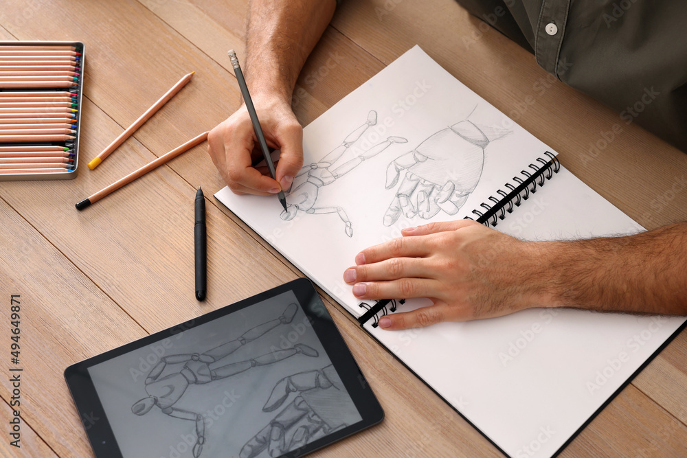 Man drawing in sketchbook with pencil at wooden table, closeup Stock Photo  | Adobe Stock