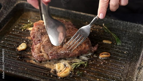 Chef flipping ribeye steak on grill pan