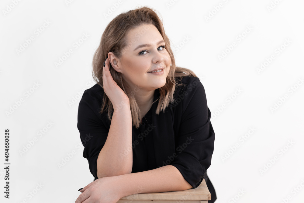 Portrait of pretty middle-aged fat plus-size woman titivating long dark hair wearing black cardigan, sitting at table. Portrait of pretty middle-aged fat plus-size woman titivating long dark hair wearing black cardigan, sitting at table.