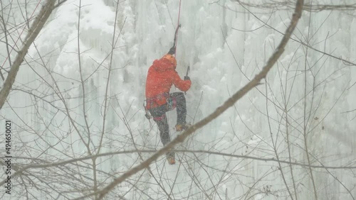 Person climbing ice waterfall during snowfall, view trough branches, Niagara Escapment photo