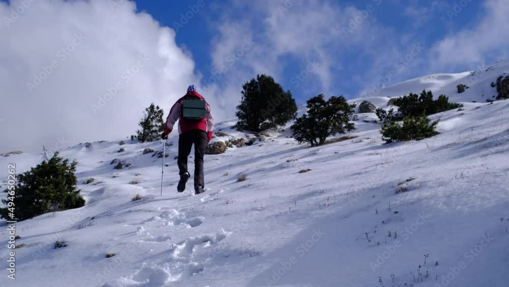 Climber reaches the top of snowy mountain on sunny winter day. Cold weather, snow on hills. Winter hiking. Climber reaches the top of snowy mountain on sunny winter day. Cold weather, snow on hills. Winter hiking.
