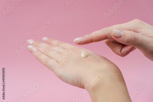 Female hands moisturizer the cream on pink background. Skincare  Spa salon