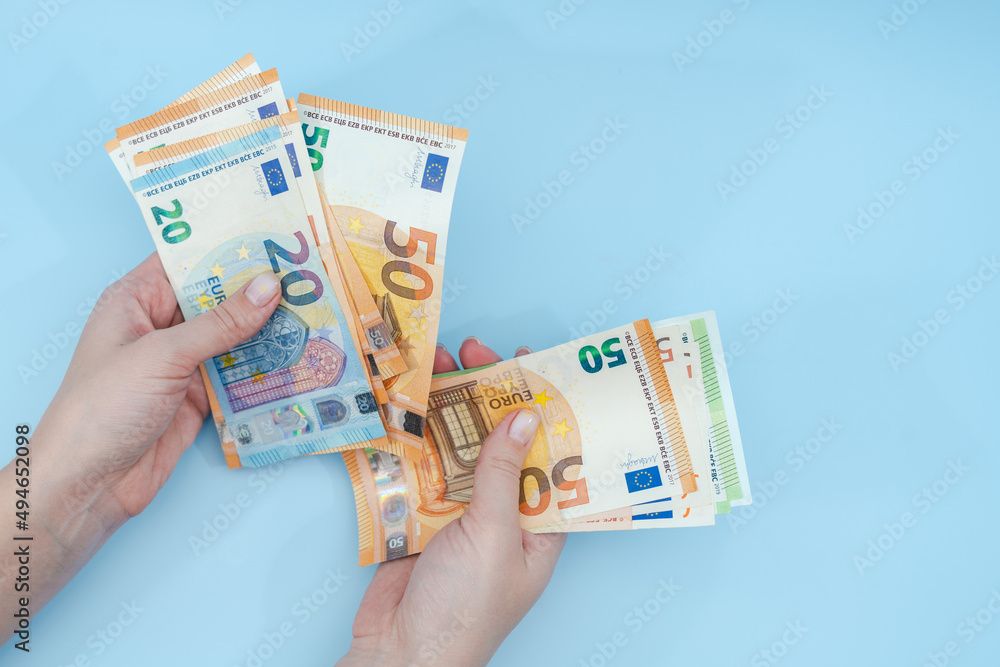 Female hands counting stack of euro banknotes on blue background. Money. Business. Finance Female hands counting stack of euro banknotes on blue background. Money. Business. Finance