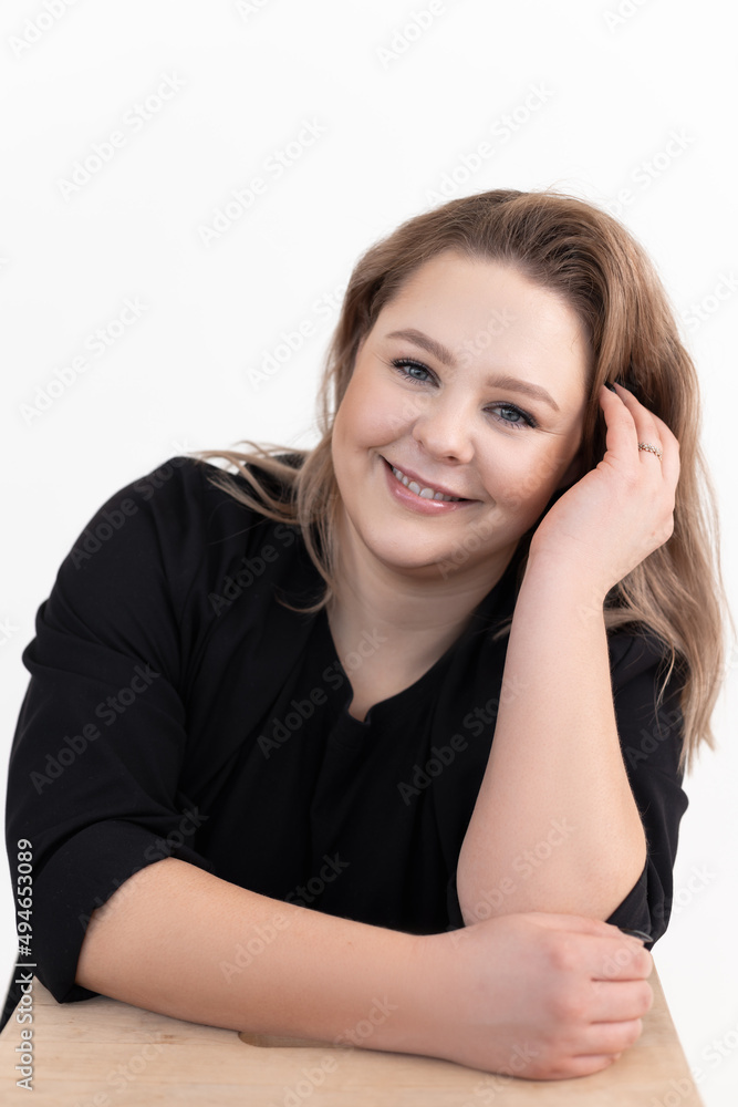 Portrait of happy pretty middle-aged fat woman with long dark hair and make-up wearing black cardigan, sitting at table. Portrait of happy pretty middle-aged fat woman with long dark hair and make-up wearing black cardigan, sitting at table.
