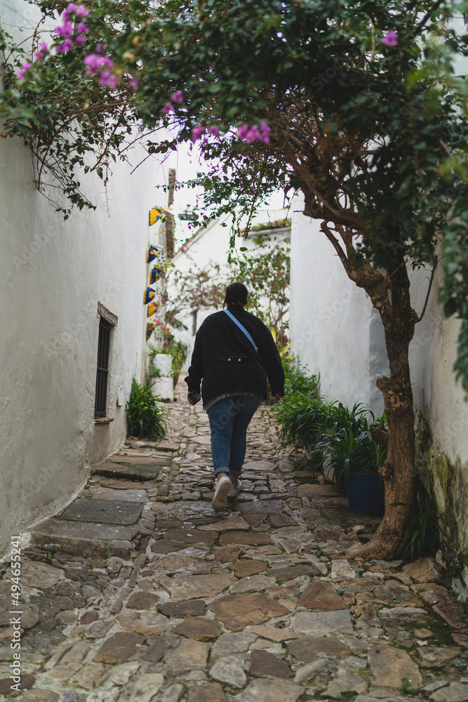 Chica joven guapa paseando por pasillos de pueblo blanco mientras sonríe y realiza fotografías Chica joven guapa paseando por pasillos de pueblo blanco mientras sonríe y realiza fotografías
