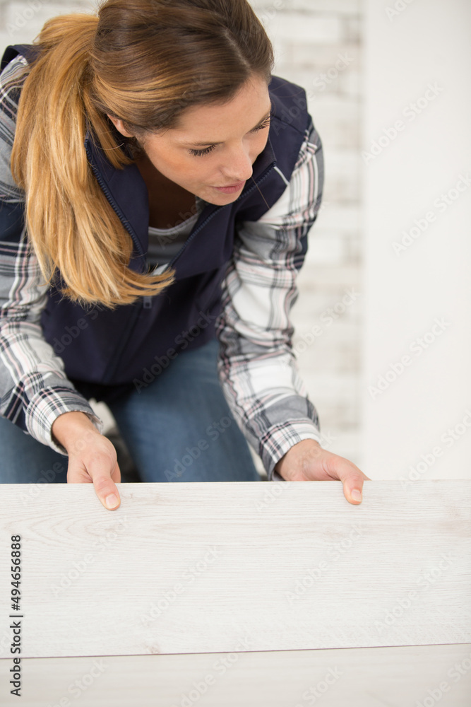 woman fitting flooring planks together woman fitting flooring planks together