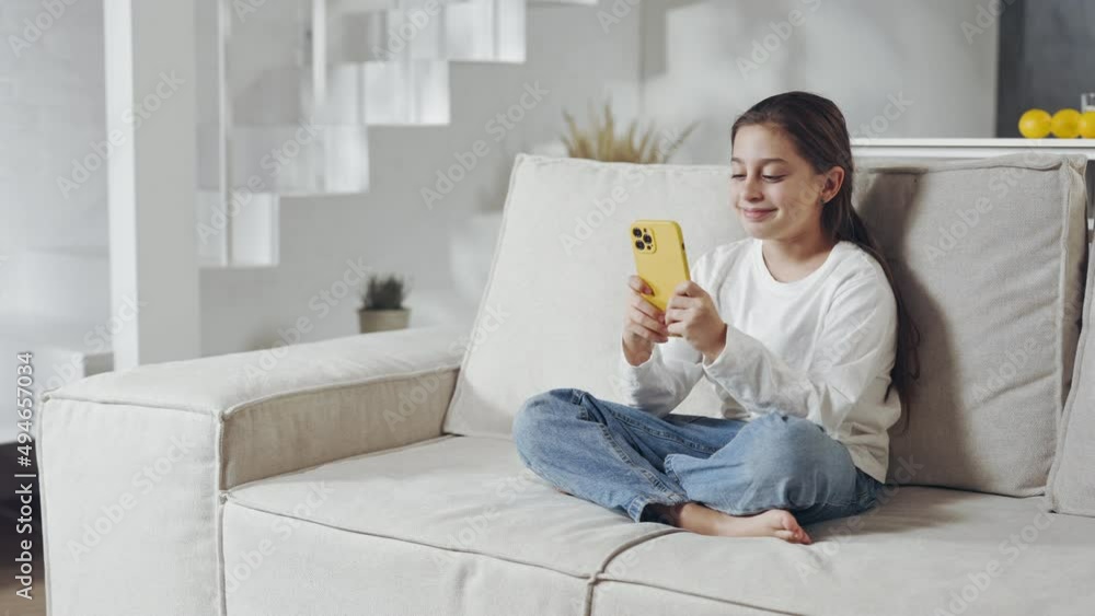 Pretty caucasian teen using smartphone on couch Pretty caucasian teen using smartphone on couch