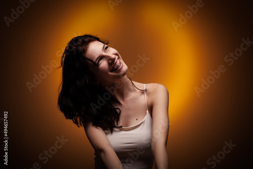 Teenage girl with dental braces. Studio portrait on neon orange colored background..