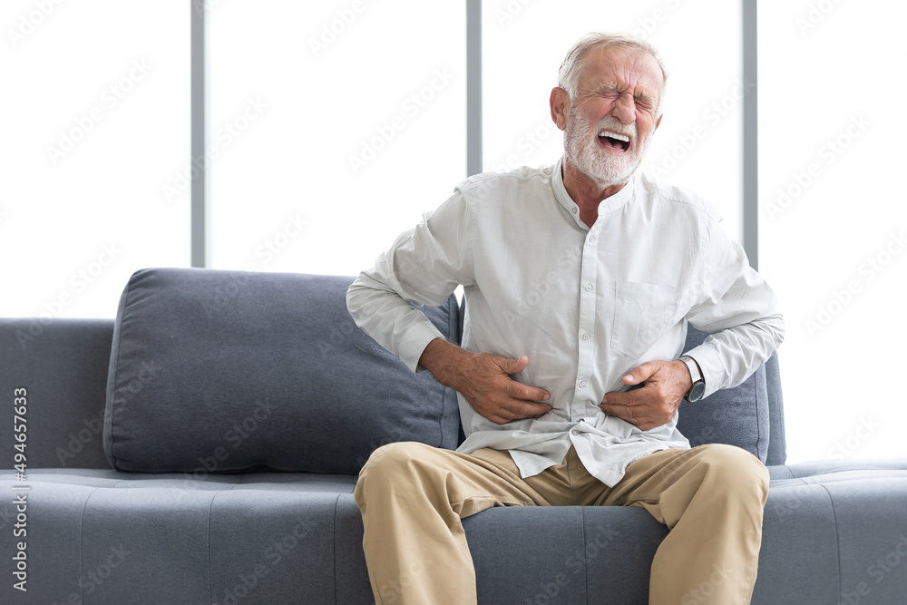 senior man have a stomachache and holding stomach on sofa senior man have a stomachache and holding stomach on sofa