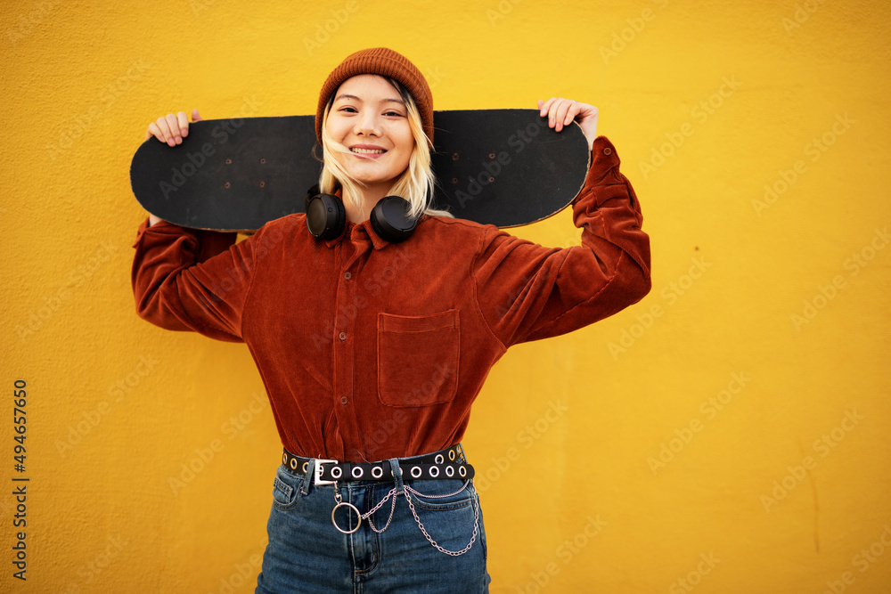 Portrait of fashion woman with skateboard. Urban woman listening the music.. Portrait of fashion woman with skateboard. Urban woman listening the music..