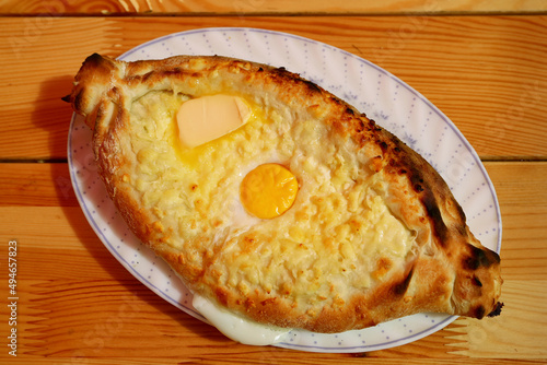 Plate of Adjaruli Khachapuri, Traditional Georgian Cheese and Egg Bread Served on Wooden Table
