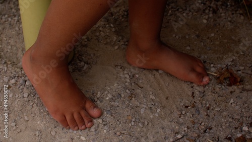 A close-up of naked feet of kid on the sand in the playground. Being barefoot boosts brain development in children.