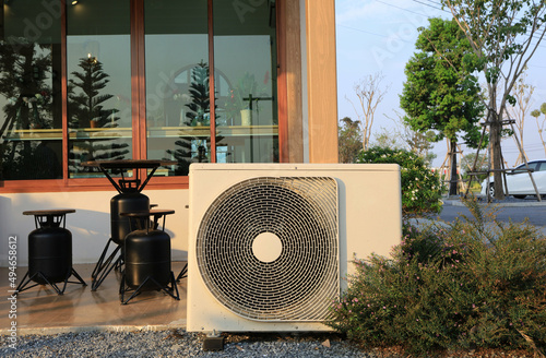 Air conditioner ourdoor condensing unit construction in front of the house see inside by glass interoir. photo