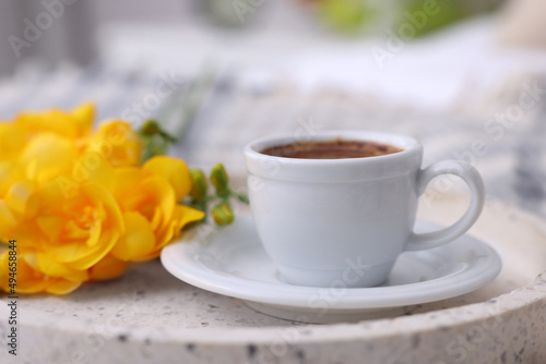 Cup of morning coffee and flowers on tray indoors, closeup