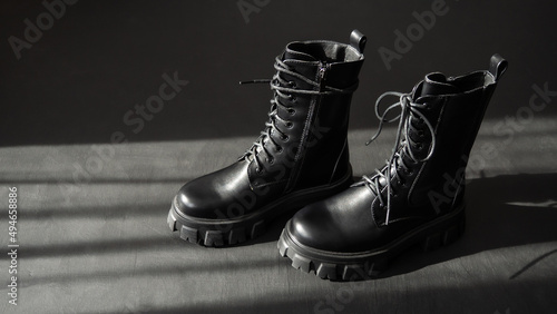 Black leather lace-up boots. Fashionable, stylish collection of women's shoes. Black background.