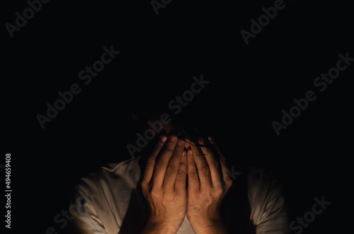 Asian miserable depressed man sitting alone in dark background. Depression and mental health concept.