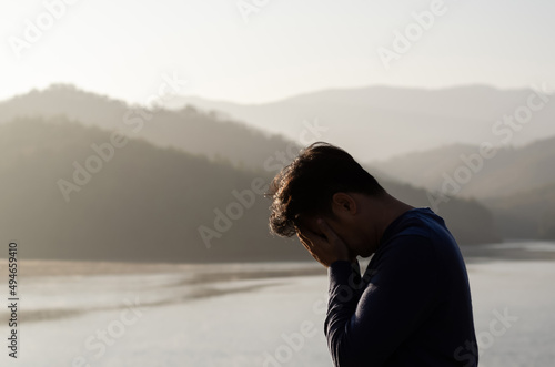 Asian miserable depressed man stand alone with mountain and lake background. Depression and mental health concept. © baramyou0708