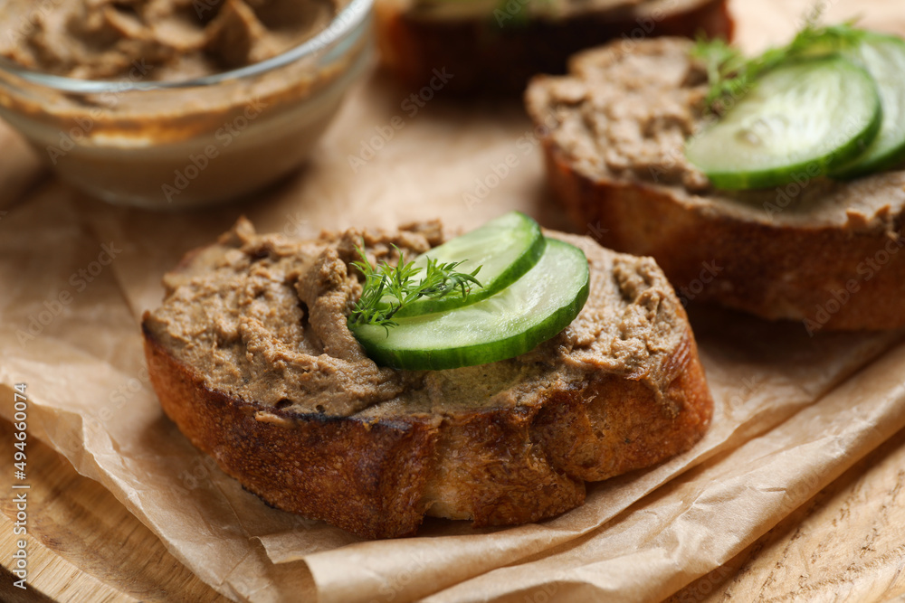 Slices of bread with delicious pate, cucumber and dill on wooden plate, closeup