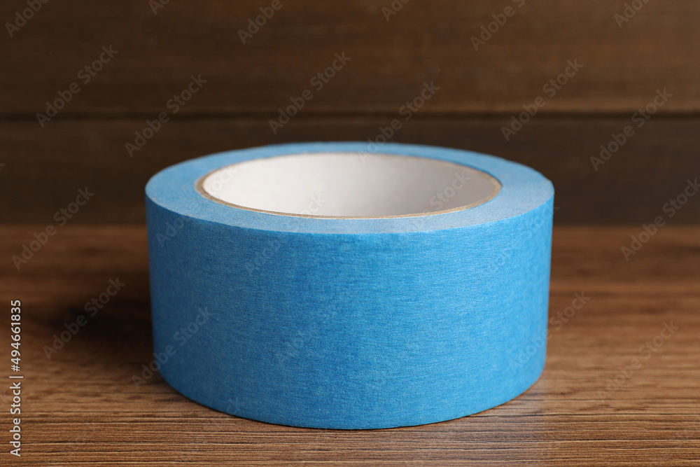 Roll of light blue adhesive tape on wooden table, closeup Roll of light blue adhesive tape on wooden table, closeup