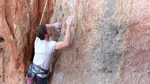 A strong man climbs a rock at a high altitude, a climber trains on the rocks, training strength and endurance