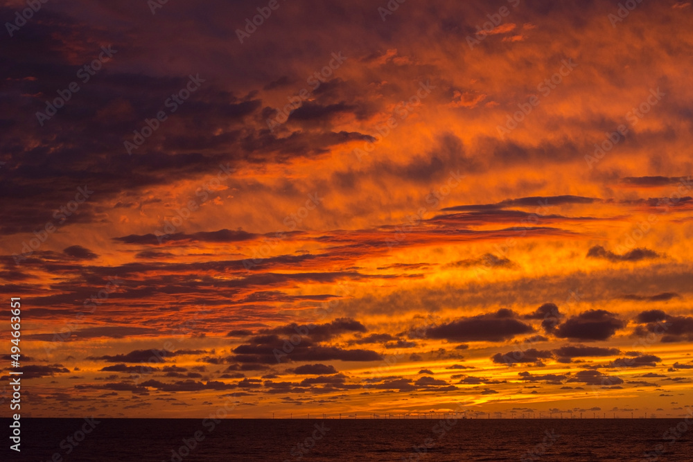 Yellow dawn with clouds. Sundown in the ocean. Orange and yellow sky in the evening