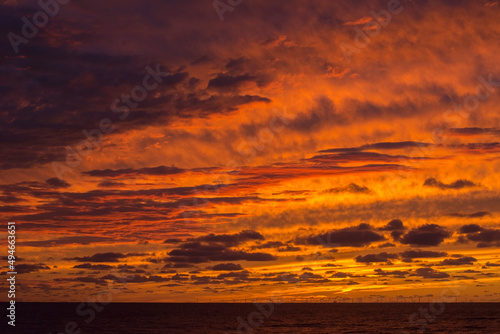 Yellow dawn with clouds. Sundown in the ocean. Orange and yellow sky in the evening