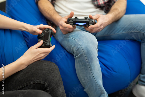 Close-up of the hands of a man and a woman enjoying playing video games with a console gamepad in their hands.