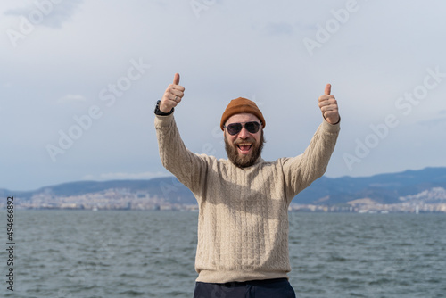 Tourist man take photo with sea and mountain background while traveling around the sea city in Europe. Happy guy smiling at camera outdoors - Happy lifestyle and technology concept