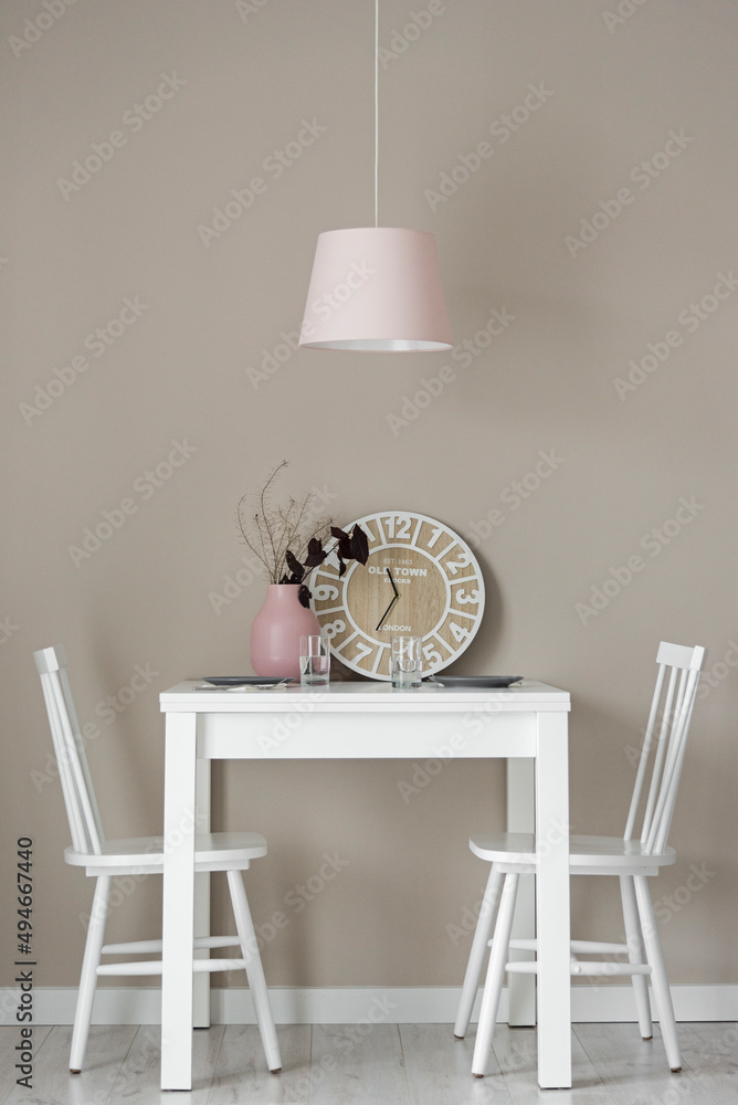 Jadalnia w kolorach beżowych, białych i różowych. Firanka i zasłony.  Stolik do jedzenia z wisząca różową lampą. Zegar i ozdoby - obrazy, fototapety, plakaty 