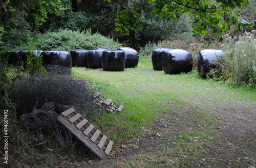 Black Plastic Covered Bales in Corner of Wooded Field 