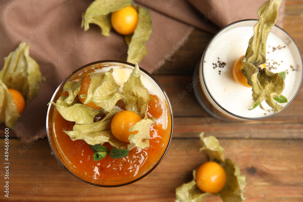 Delicious dessert decorated with physalis fruit on wooden table, flat lay Delicious dessert decorated with physalis fruit on wooden table, flat lay