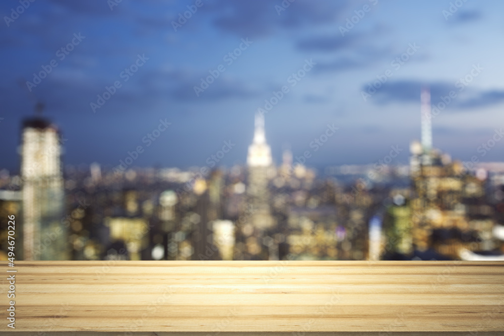 Empty wooden table top with beautiful blurry skyscrapers at evening on background, mock up