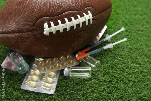 Foto American football ball and different drugs on green grass, closeup
