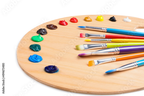 Palette with paints and brushes on white background, closeup. Artist equipment