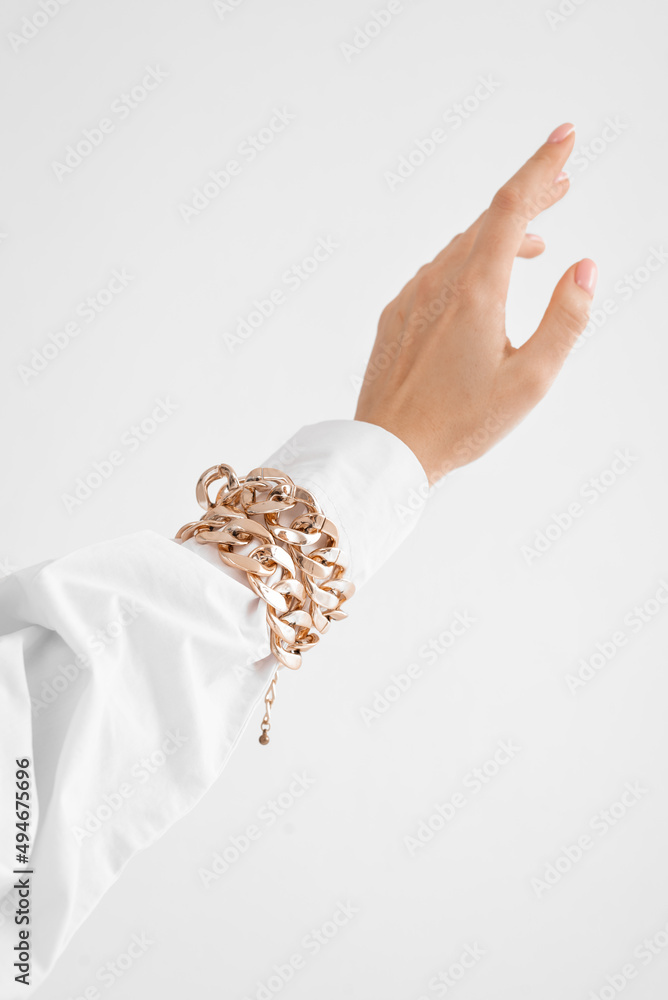 a woman's hand in a shirt with a gold bracelet on a white background, a beautiful palm on a white background (copy space) a woman's hand in a shirt with a gold bracelet on a white background, a beautiful palm on a white background (copy space)