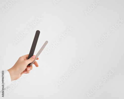 a hand with a nail file on white background with (copy space, horizontally)