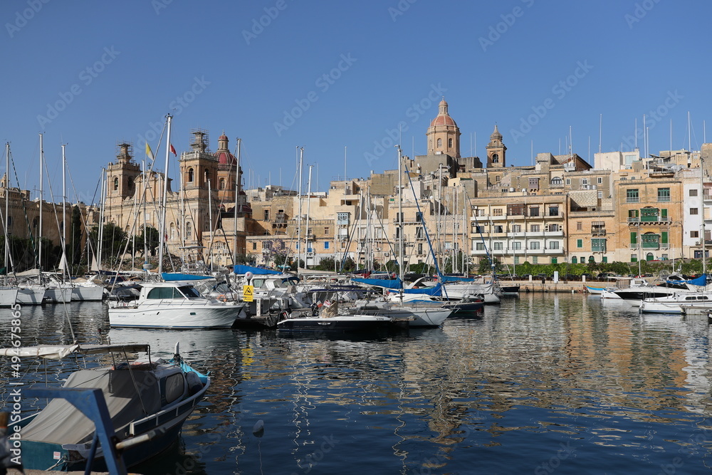 Boats are moored in a small bay in the Maltese city in the sunny summer day