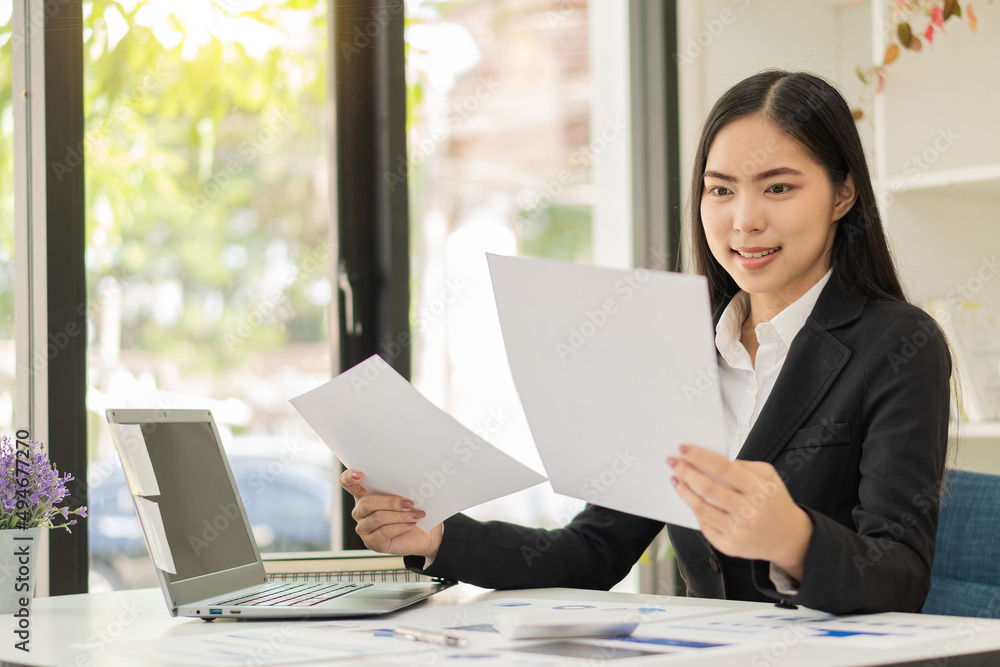 Asian businesswoman sitting at a desk young woman working data analysis charts financial documents with laptop in the office Asian businesswoman sitting at a desk young woman working data analysis charts financial documents with laptop in the office