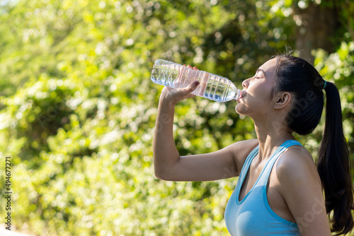 Asian women drink water after jogging, play sports with clear plastic bottles, and smile at you in the park.